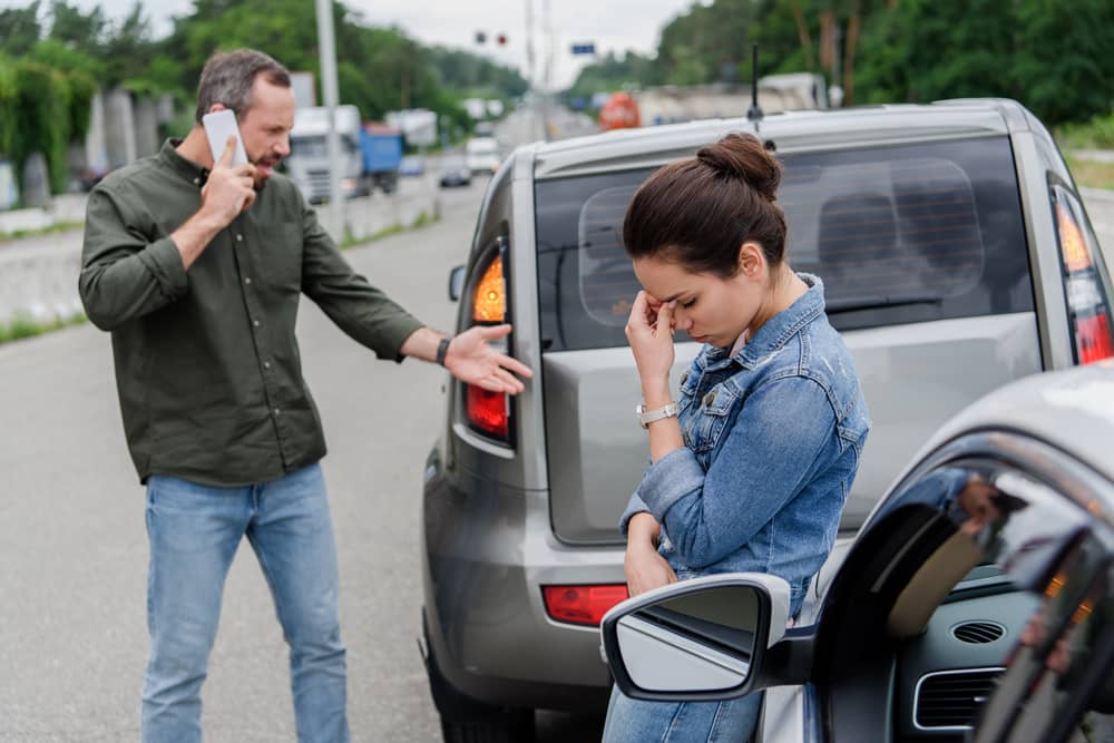 Zwei Beteiligte bei einem Autounfall, die den Unfall dokumentieren.